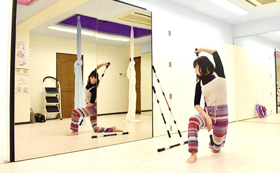 棒をもって鏡を見ながらトレーニングする女性