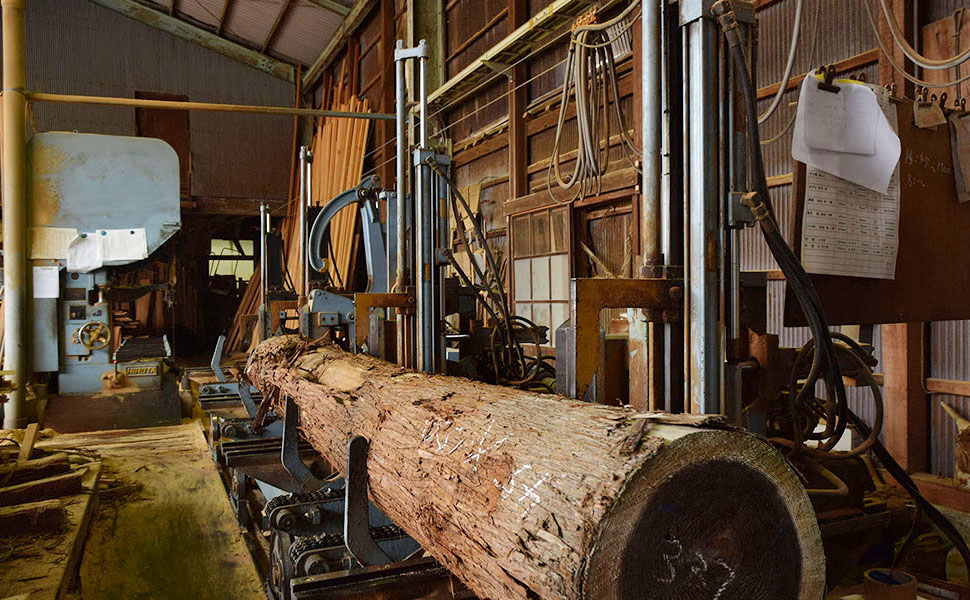 中川製材所の木材加工作業場で丸太を切り出す機械にセットされた丸太