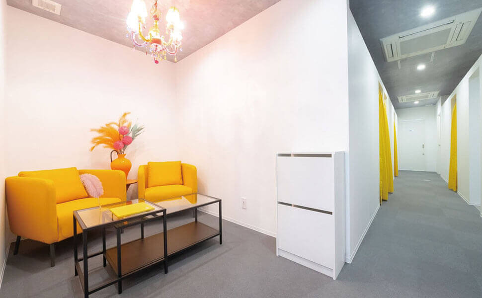 オレンジのソファーに、白い壁、シャンデリアが雰囲気抜群