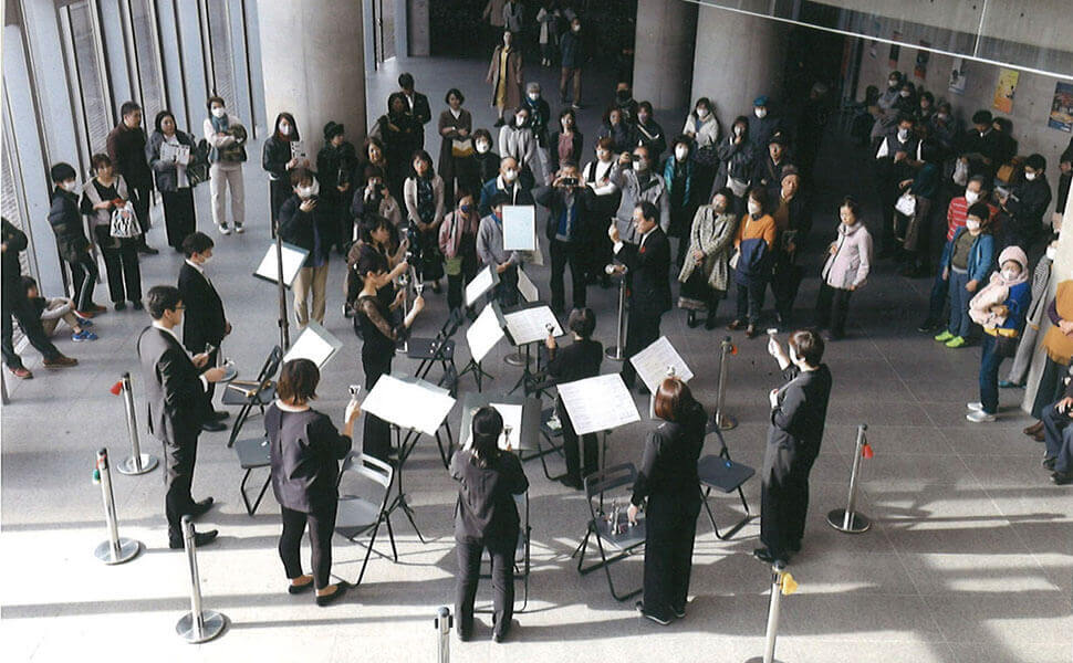 数名の演奏家がハンドベルによるミニ演奏会をロビーで開いている