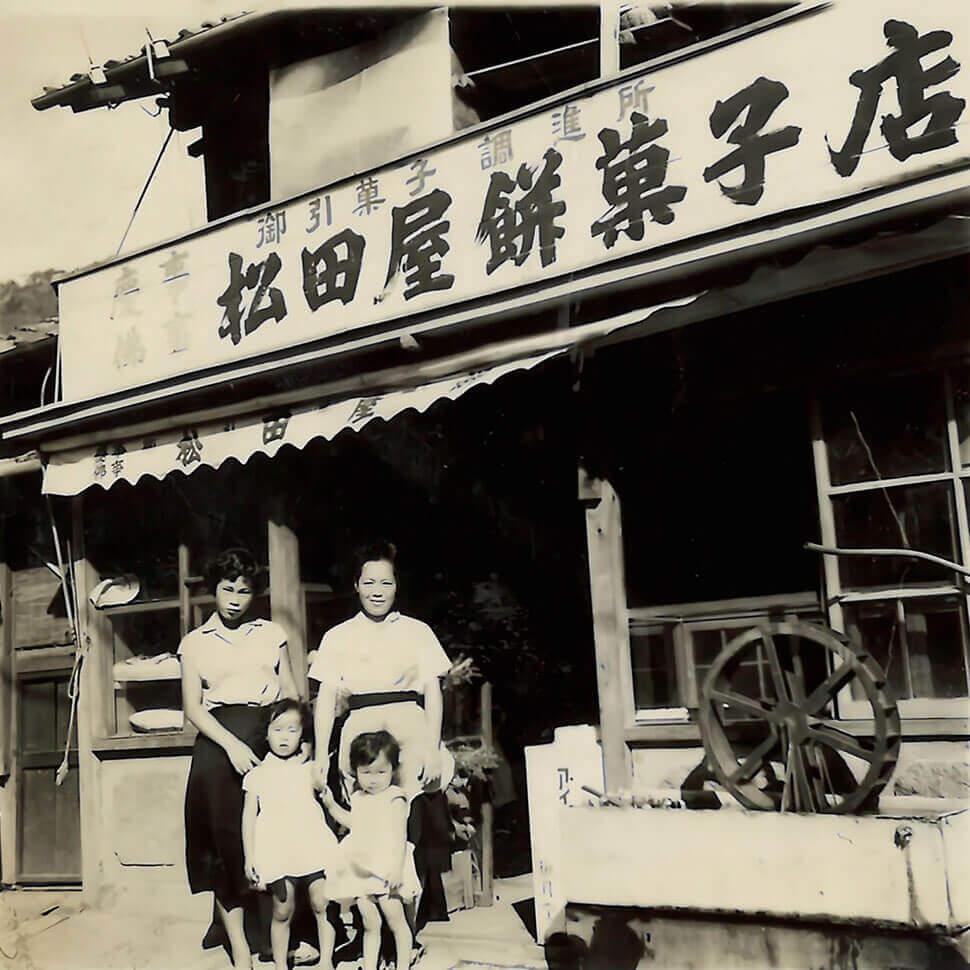 古い写真に、女性2名と子供2名が店舗前に立っている