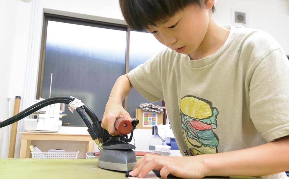 小学生の男の子がアイロンをあてている