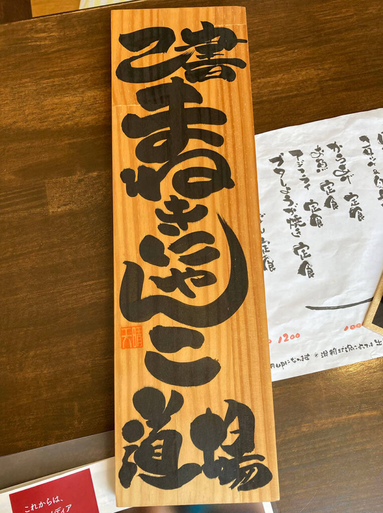 細長い木の板に書かれた「まねききゃんこ道場」の文字